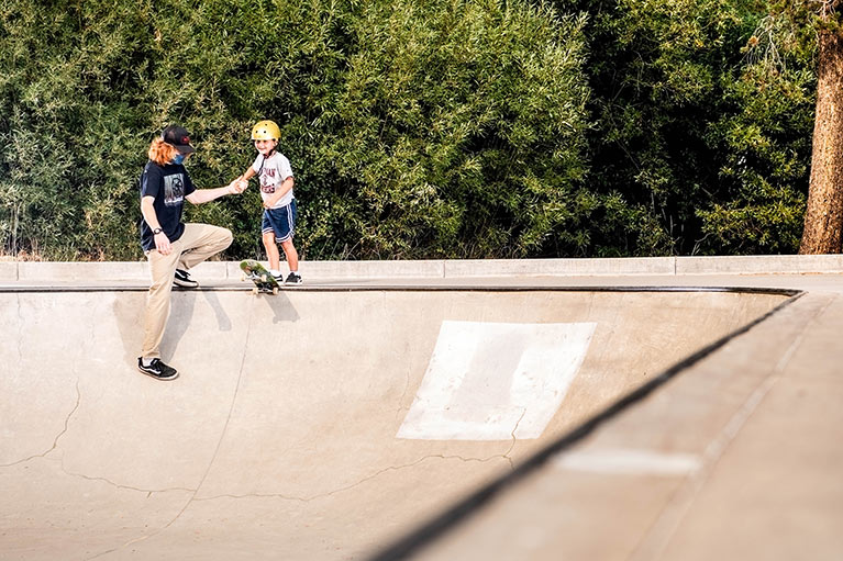 Coach cedar helps boy drop into bowl at Incline Village Skate School camp