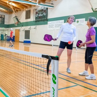 ladies with pickleball paddles indoors