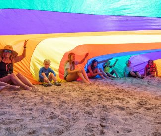 kids under parachute on beach