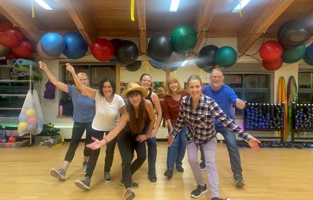line dancers pose in group fitness room