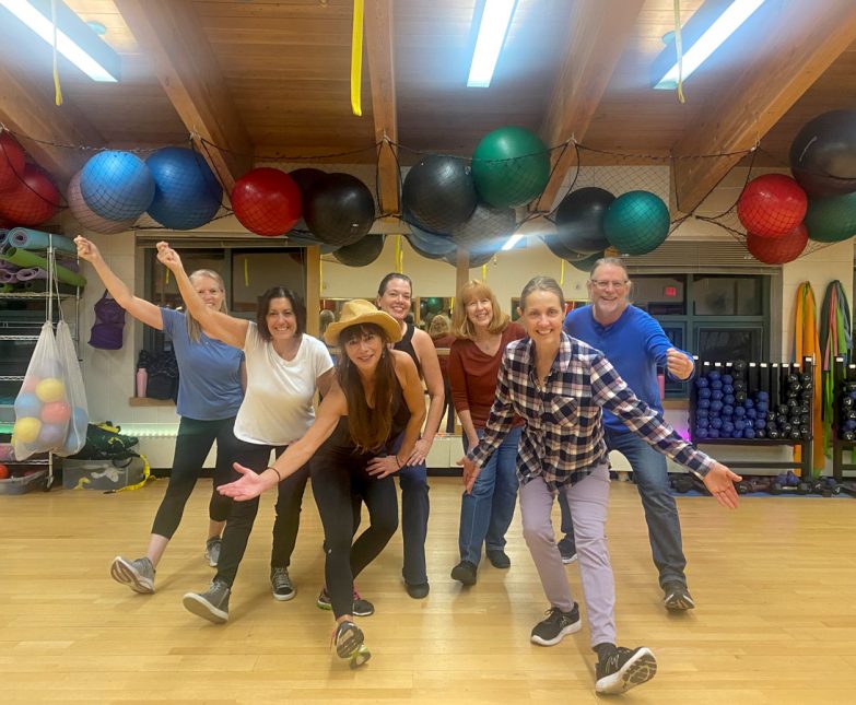 line dancers pose in group fitness room
