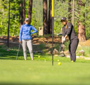 women chipping on practice green