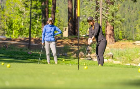 women chipping on practice green