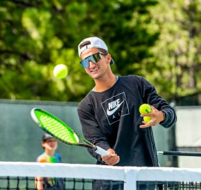 young man holding a tennis racket hitting a tennis ball