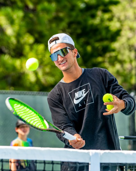 young man holding a tennis racket hitting a tennis ball