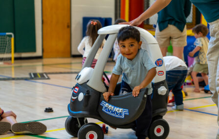boy playing ride on toy at preschool playground