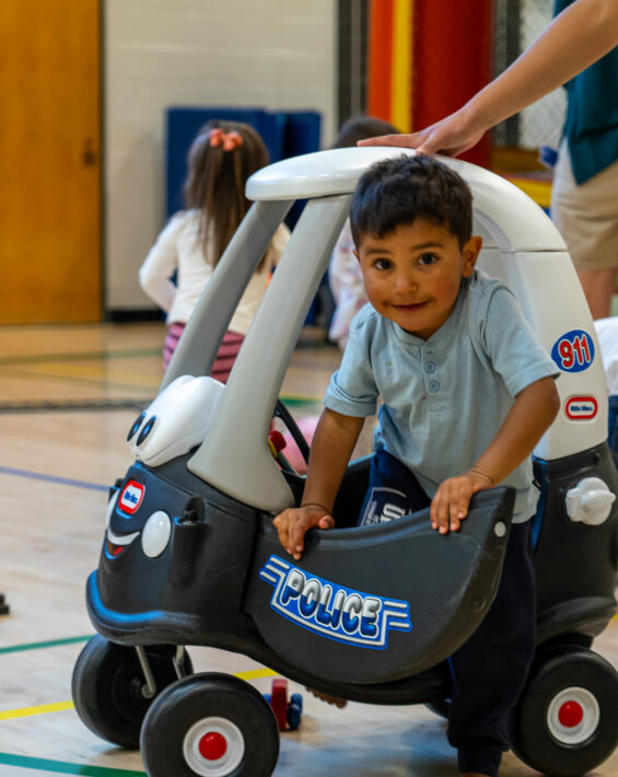 boy playing ride on toy at preschool playground