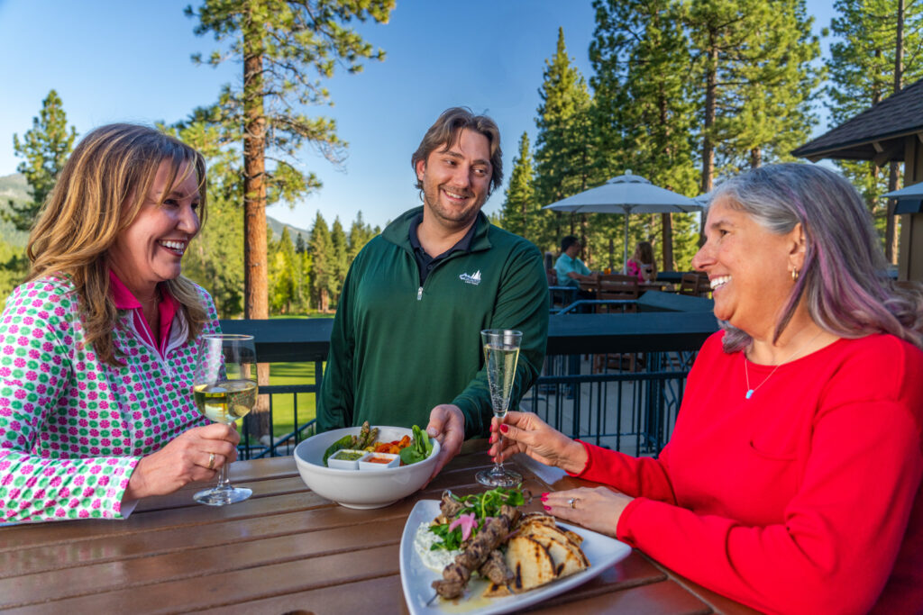 server brings food to patio table with two women
