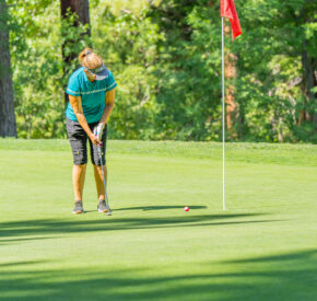 woman putts at mountain golf course