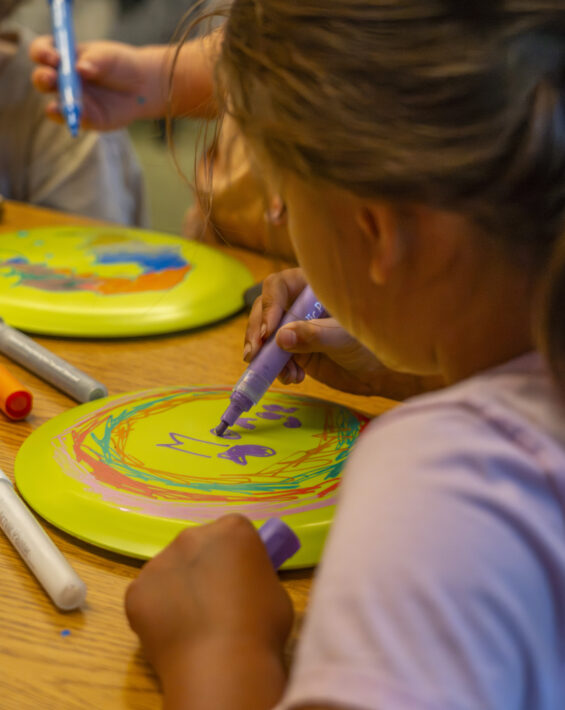 young girl coloring a frisbee