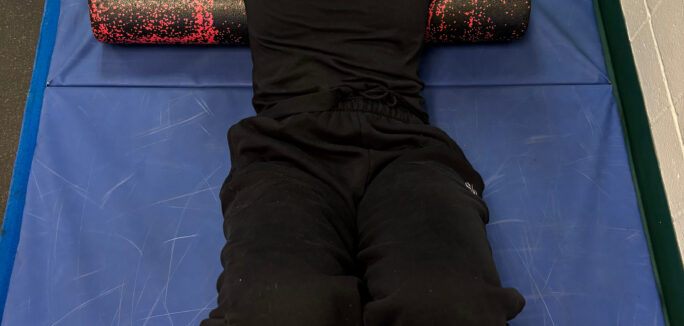 Woman laying on back on foam roller stretching